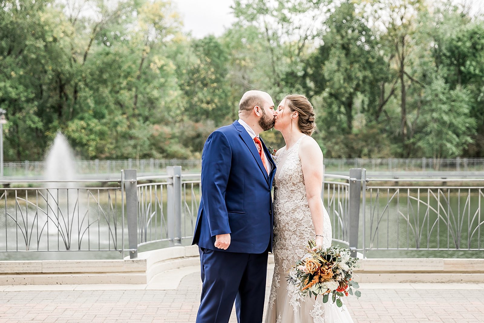 bride and groom kiss on bridge