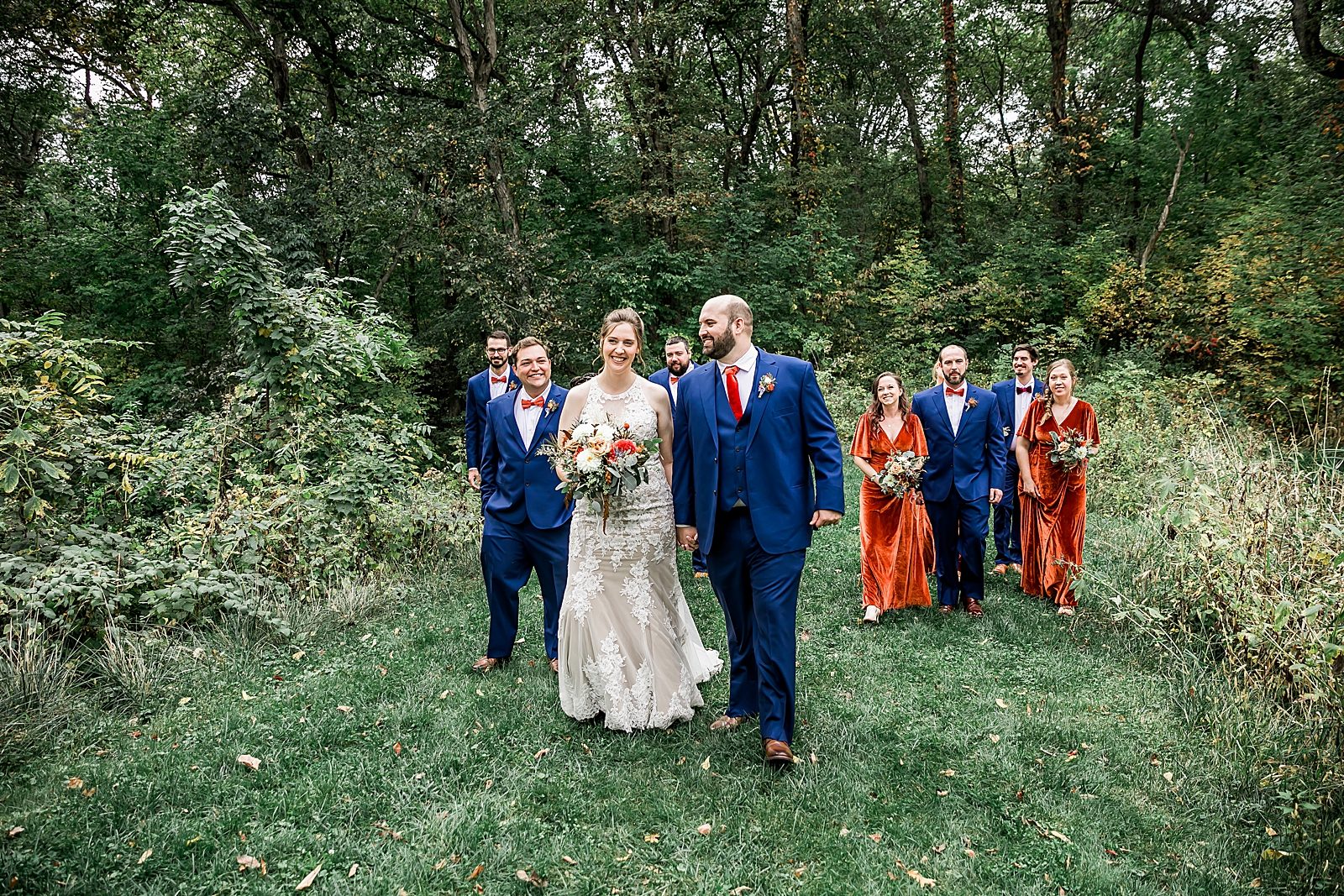 orange and blue wedding party in park walking