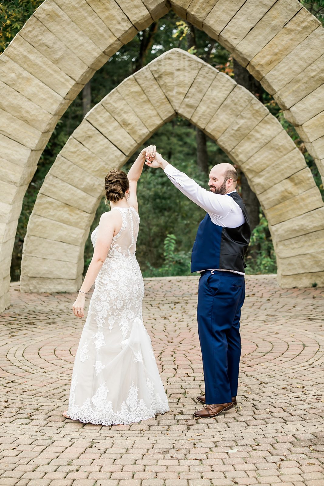 bride and groom dance under stone arches at celebration farms in iowa city