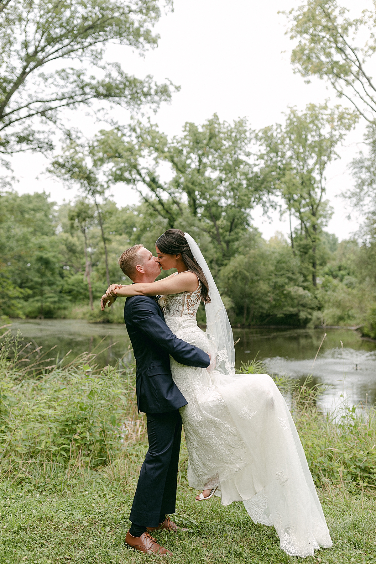 romantic bride and groom kissing at lake