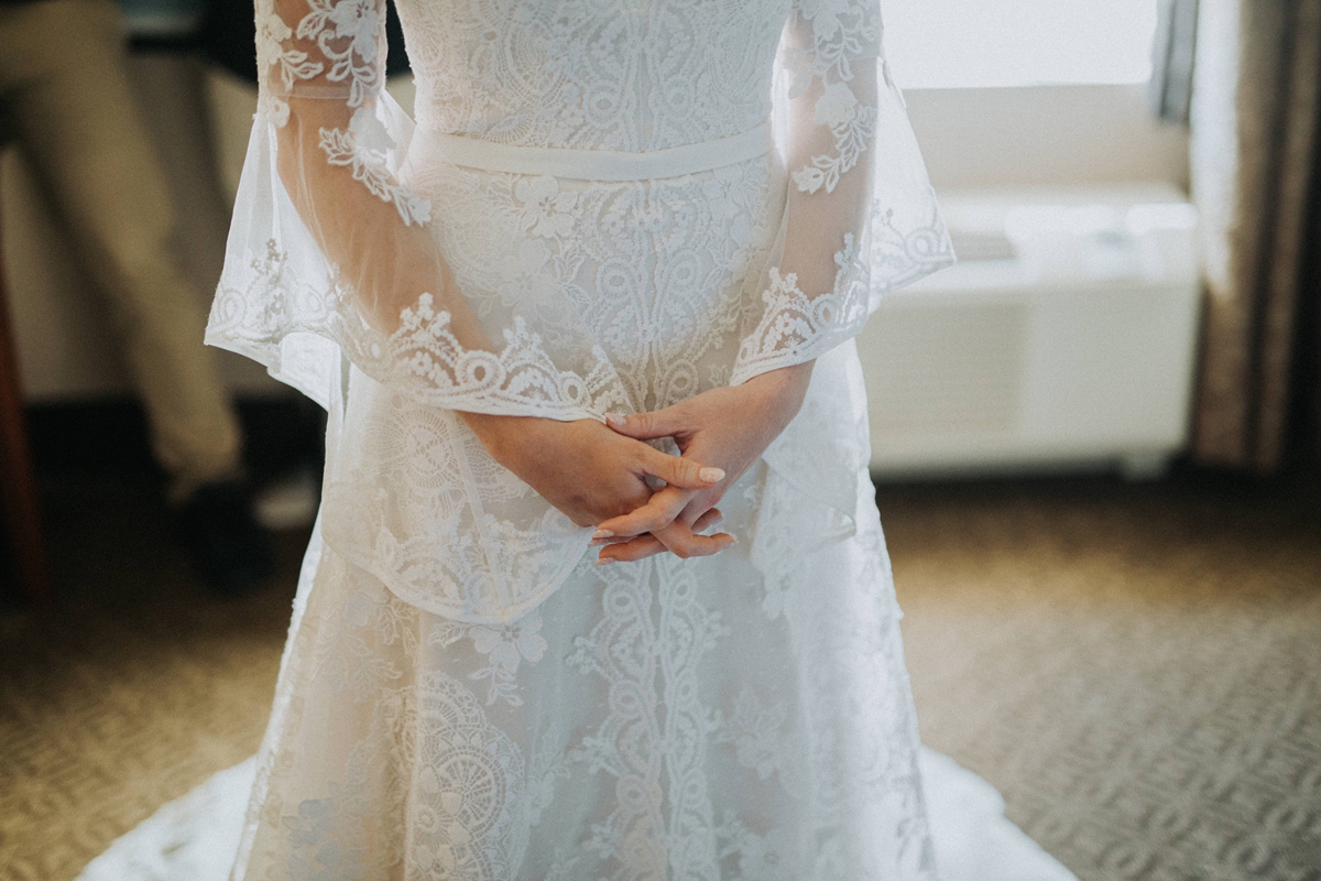 close up of bride clasping hands in front of lace wedding dress