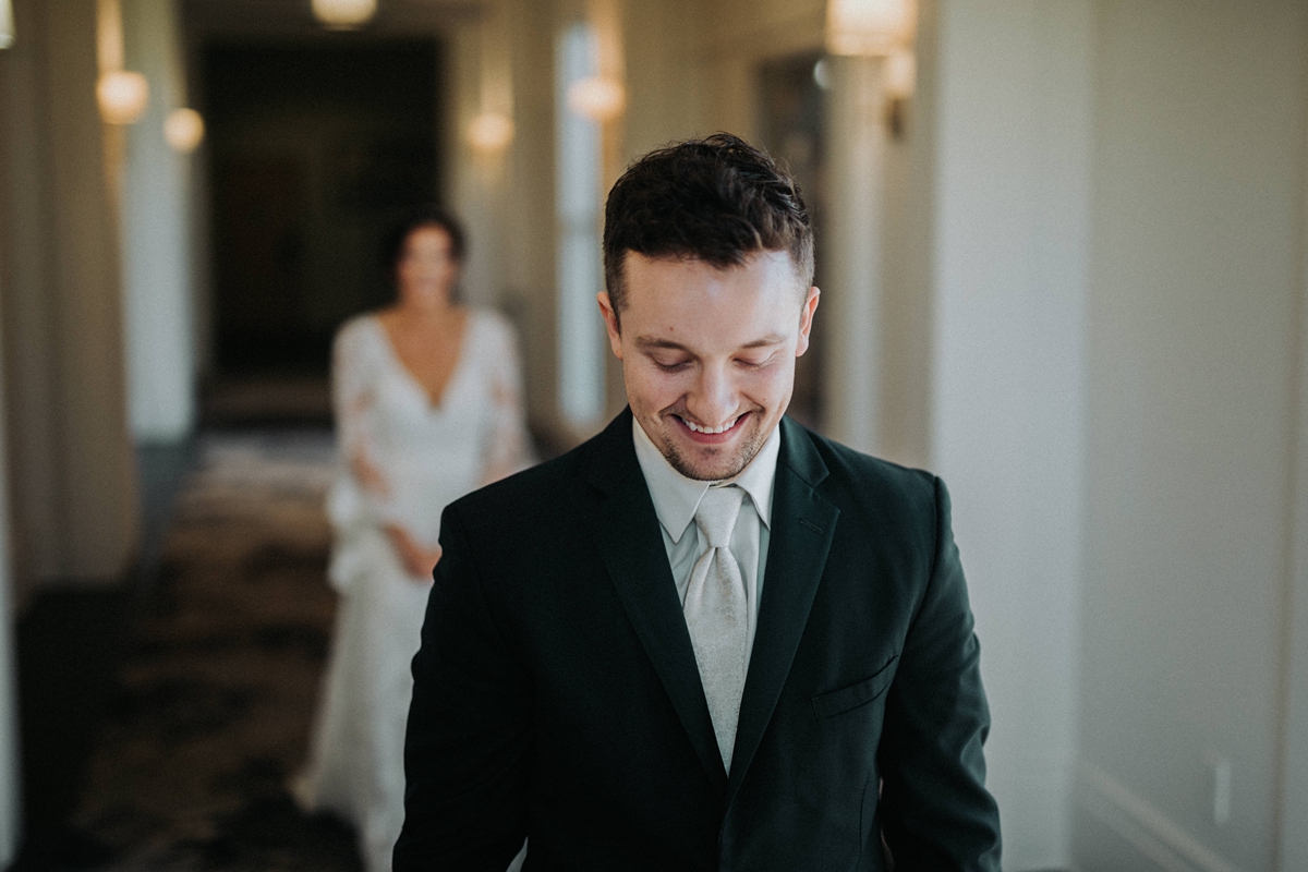 groom smiling while waiting for first look with approaching bride