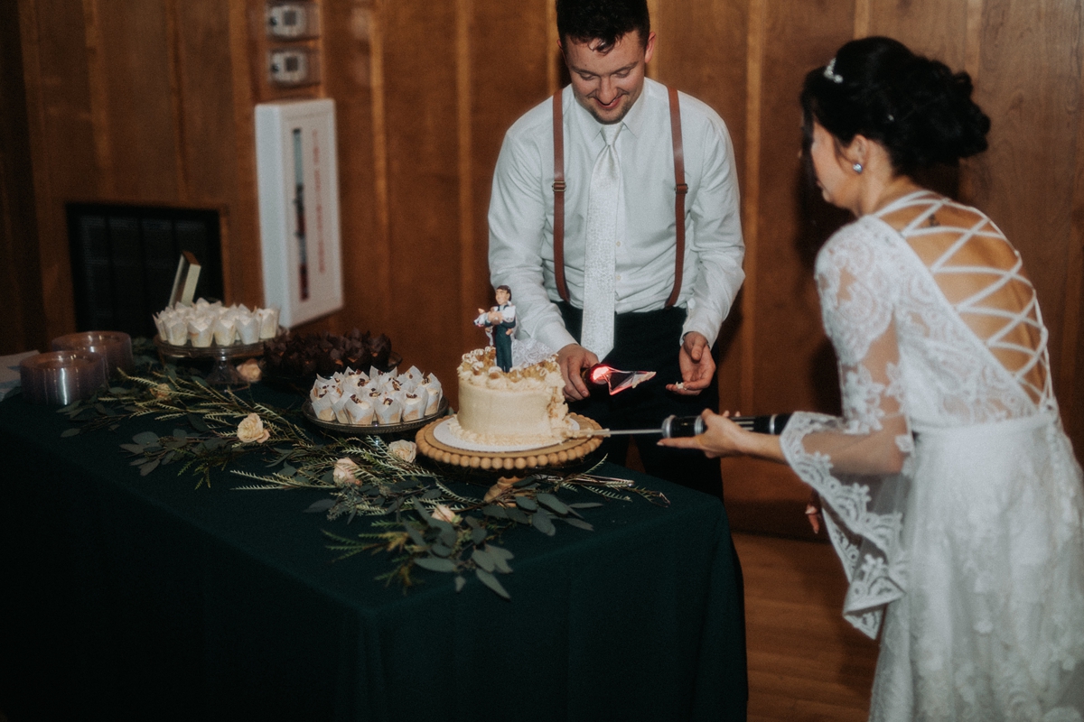 bride and groom slicing wedding cake with star wars utensils