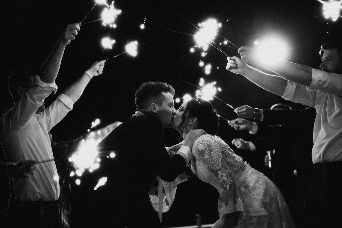 bride and groom kiss sparkler exit black and white