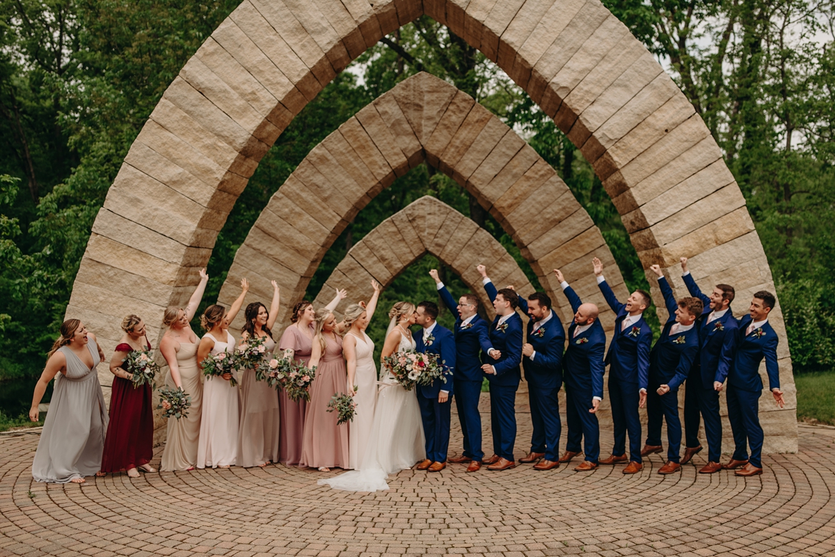 Bridal party cheersing under arches at Celebration Farm Wedding Iowa City