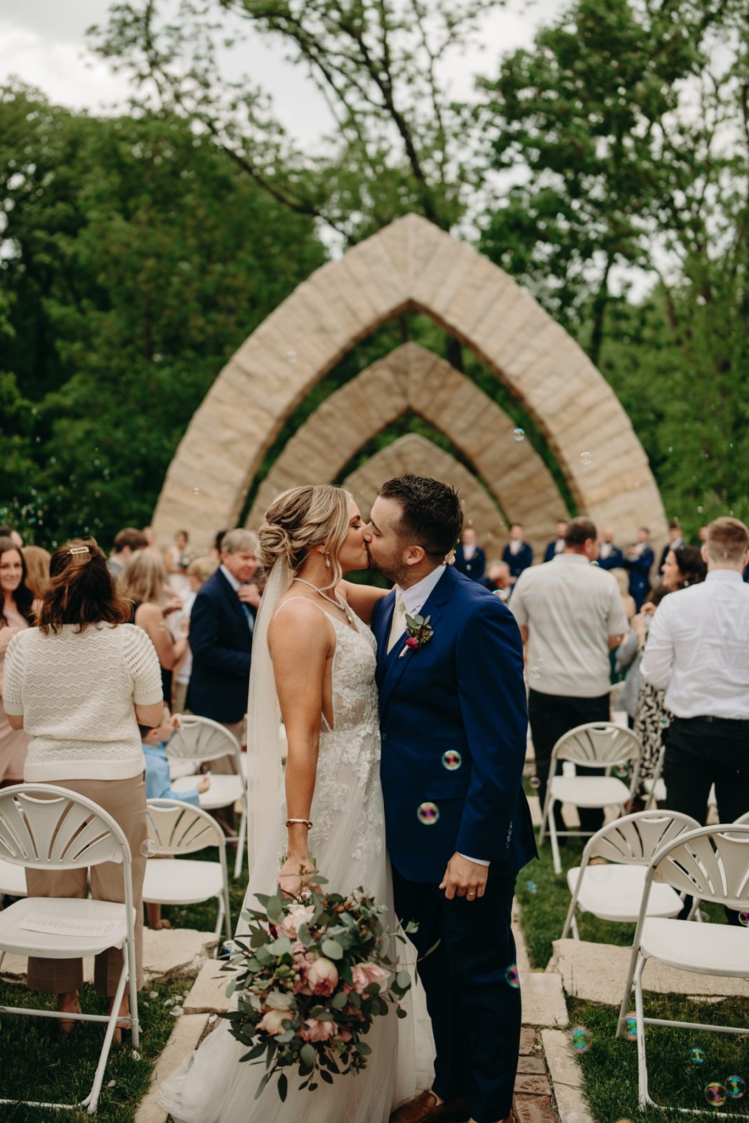 Couple kissing in front of arches at Celebration Farm Wedding Iowa City