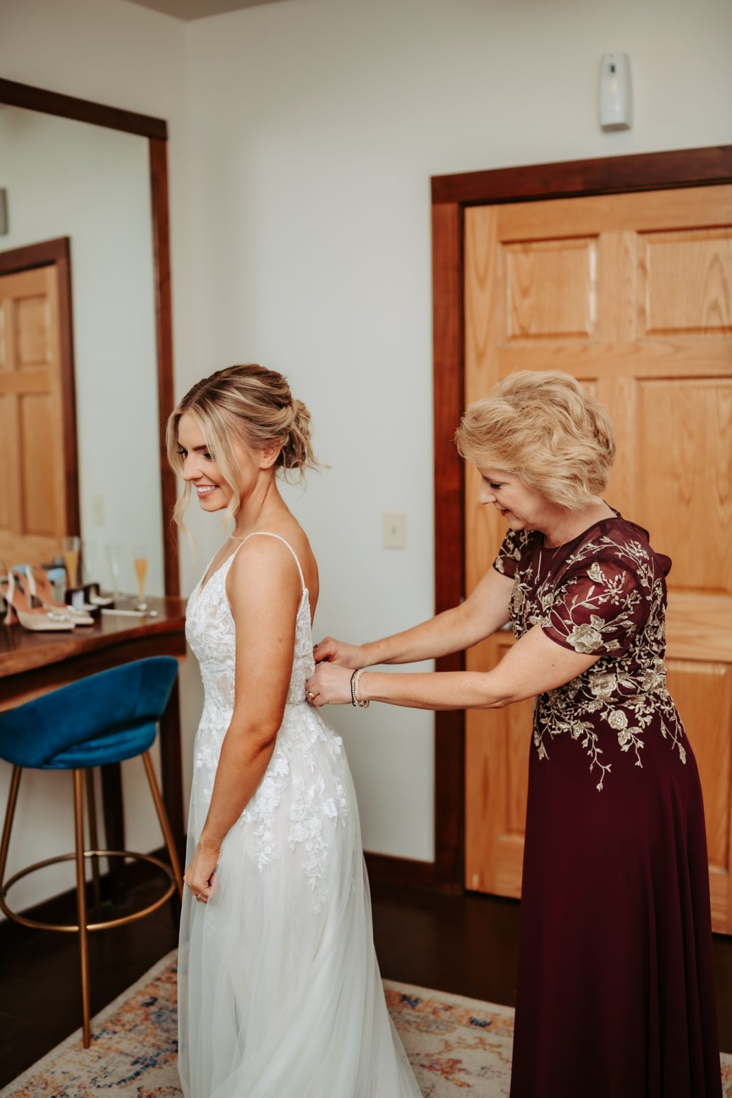 Bride's mother helping her put on wedding dress in Iowa City, Iowa