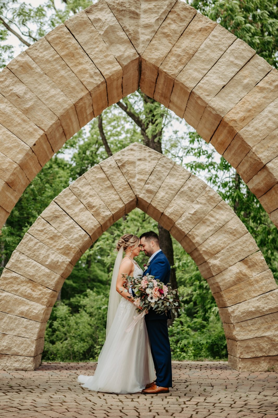 Bride and groom under stone arches at Celebration Farm Wedding Iowa City