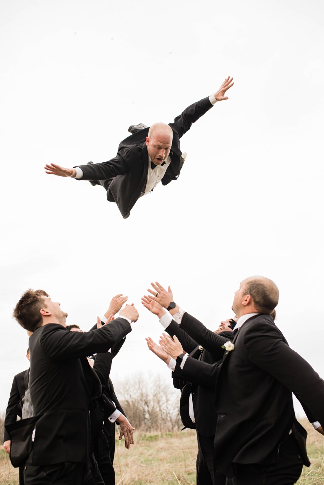 Groomsmen tossing groom into the air.
