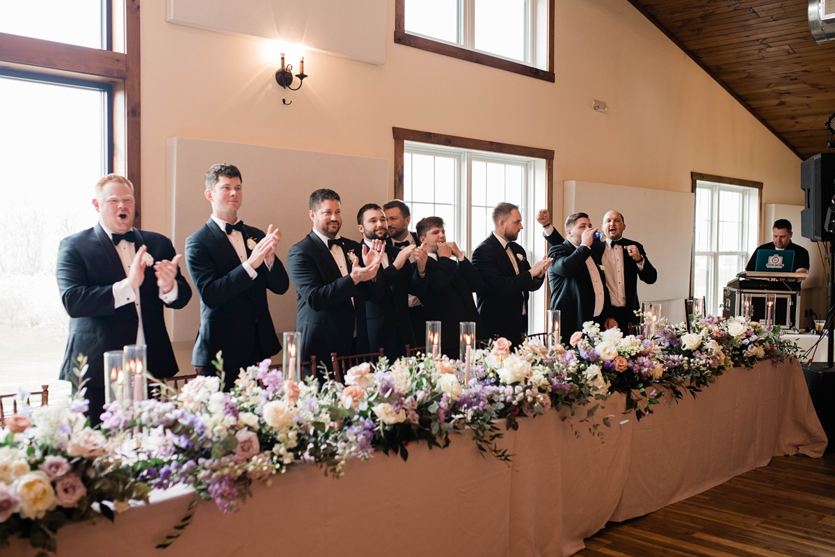 Groomsmen cheering as bride and groom enter reception