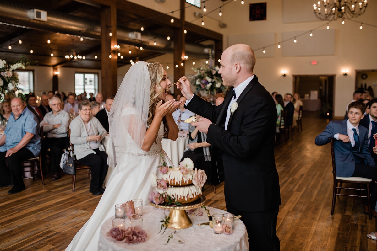 Bride and groom feeding eachother double layer bundt wedding cake