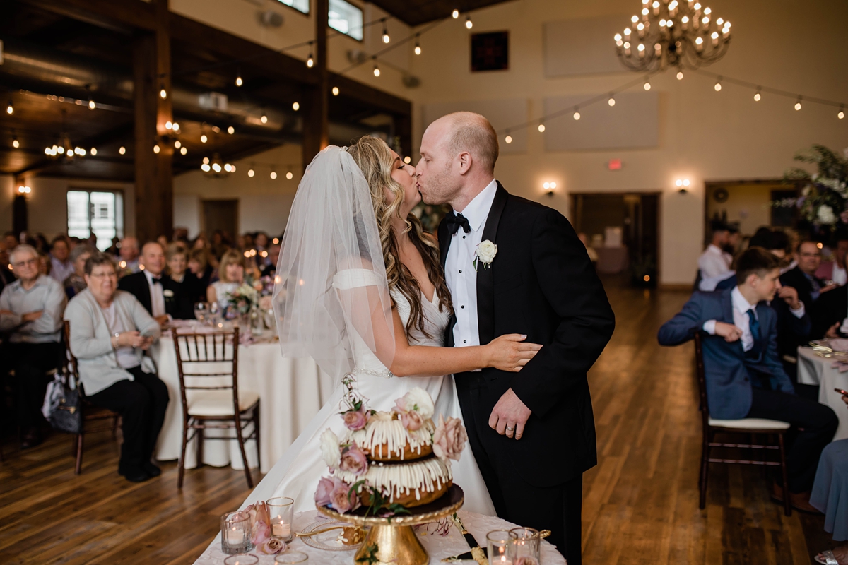 Bride and groom kissing next to double layer bundt wedding cake