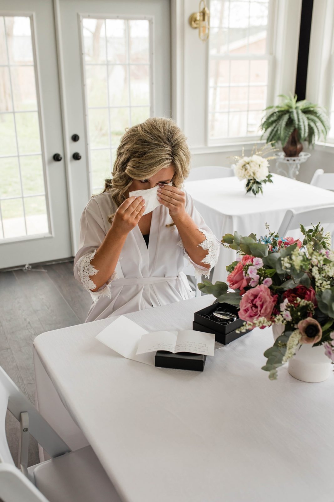 Bride wiping away happy tear while reading letter from groom before wedding.