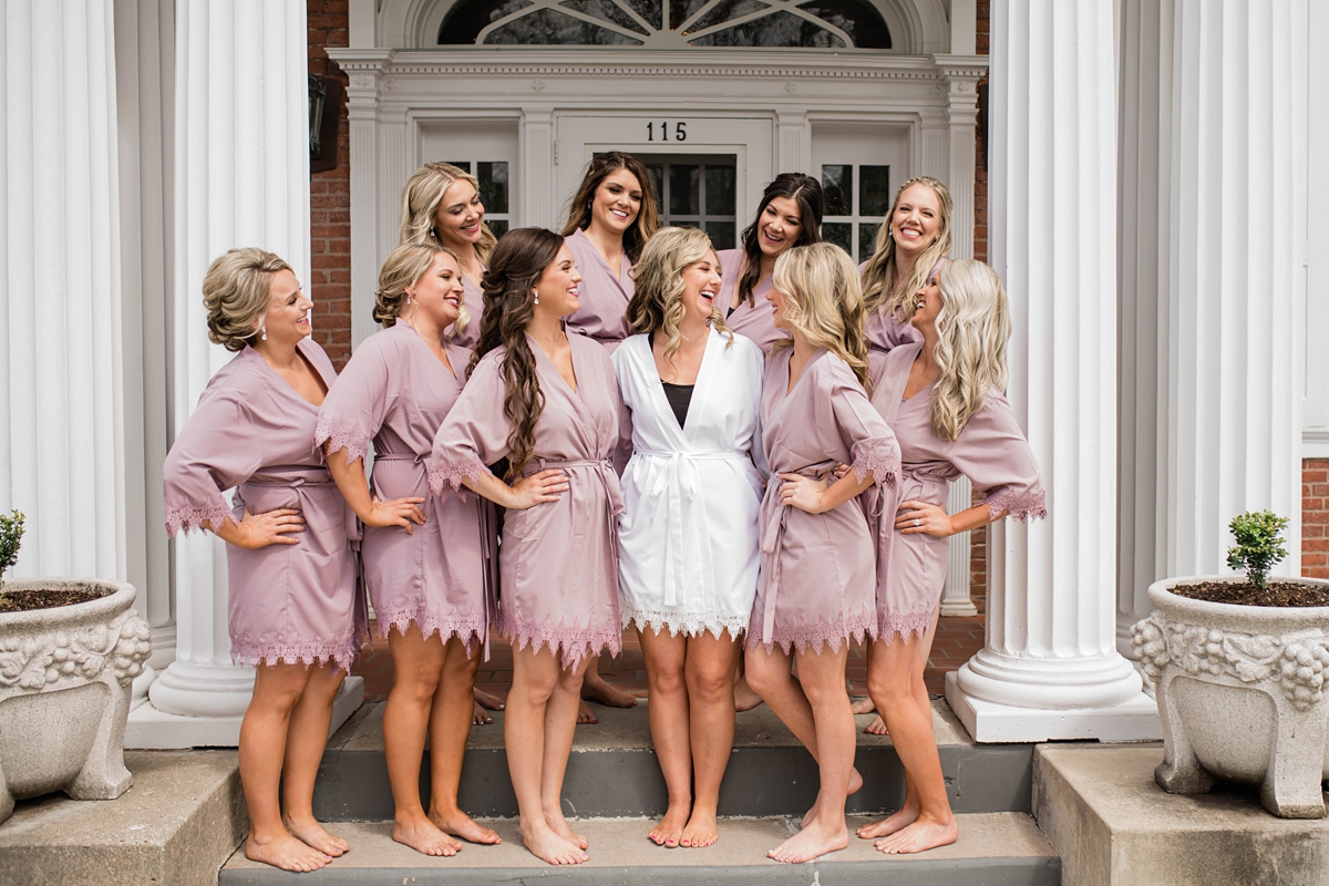 Bride and bridesmaids in lavender robes while getting ready.