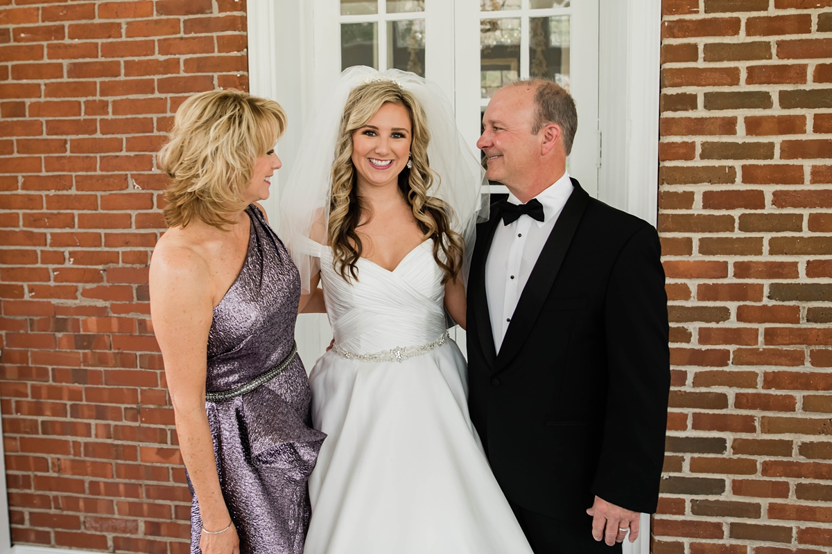 Bride smiling with parents before ceremony.