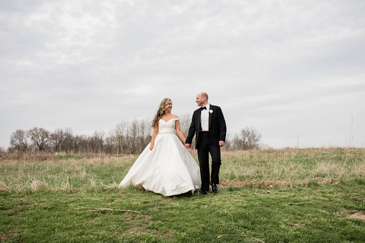 Bride and groom standing in field.