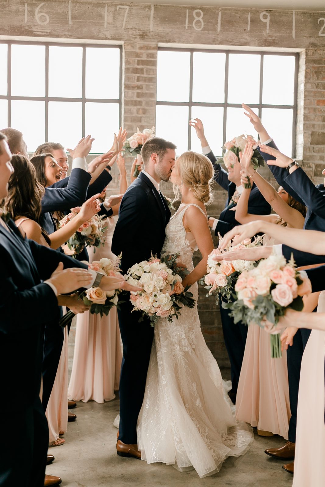 Cedar Rapids Iowa Blush Pink Harmac Wedding wedding party cheers while couple kiss