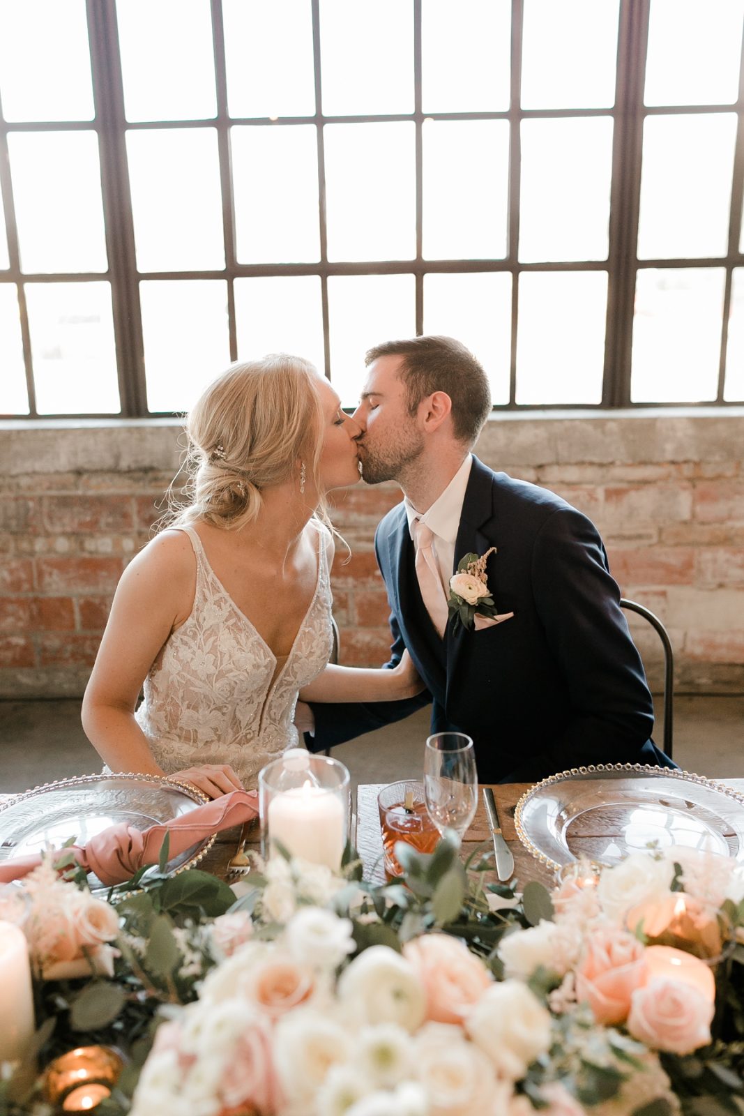 Cedar Rapids Iowa Blush Pink Harmac Wedding bride and groom kiss at reception dinner