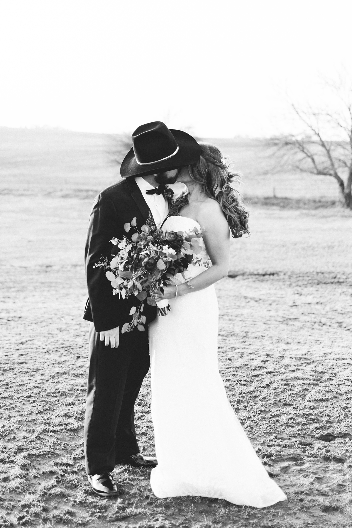 St Peter's Catholic Church in Oxford Iowa bride and groom kissing under cowboy hat