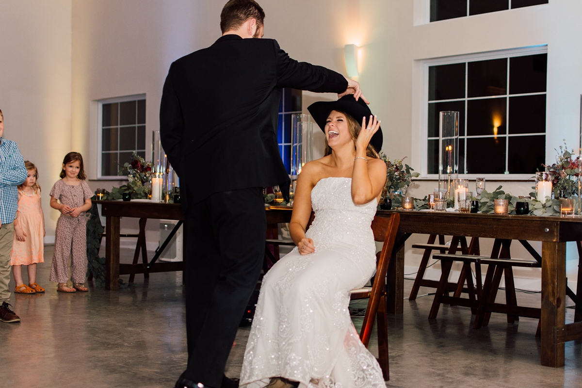 Gathering Barn Williamsburg Iowa Wedding bride and groom garter chair dance with cowboy hat