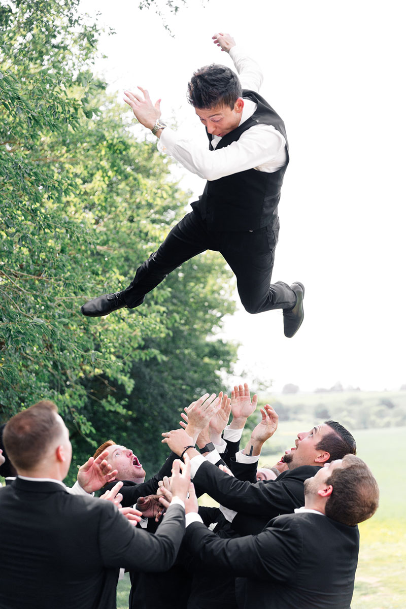 Groomsmen toss the Groom into the air during pictures