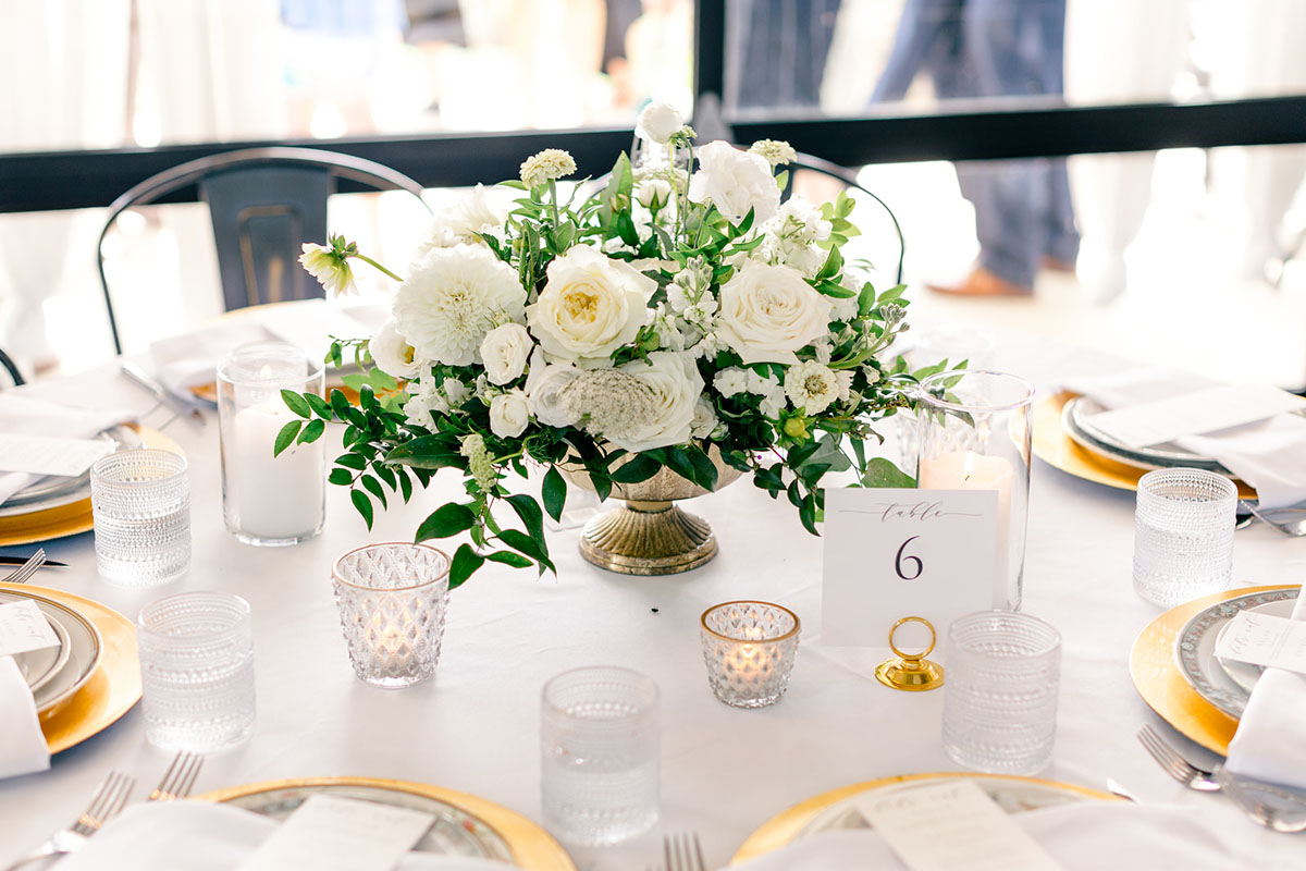 white greenery floral compote centerpiece with votive candles and table number from Allegra Iowa City
