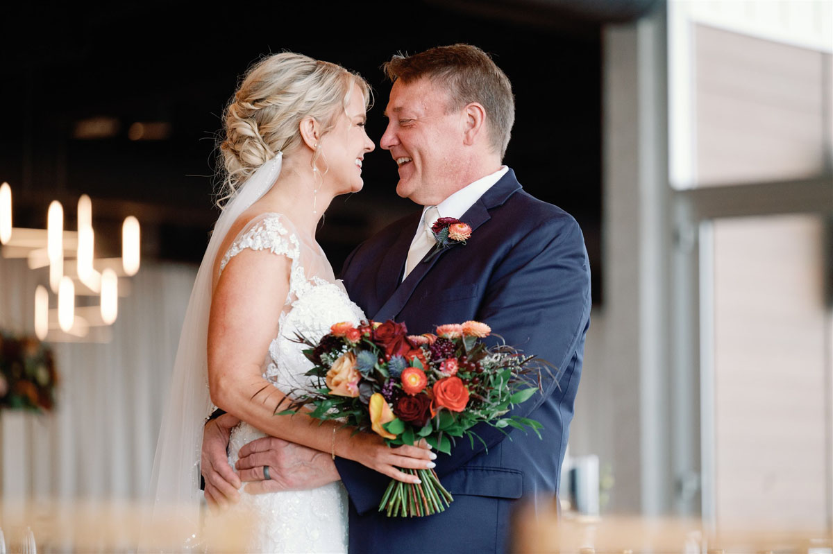 bride and groom laughing inside floral embrace